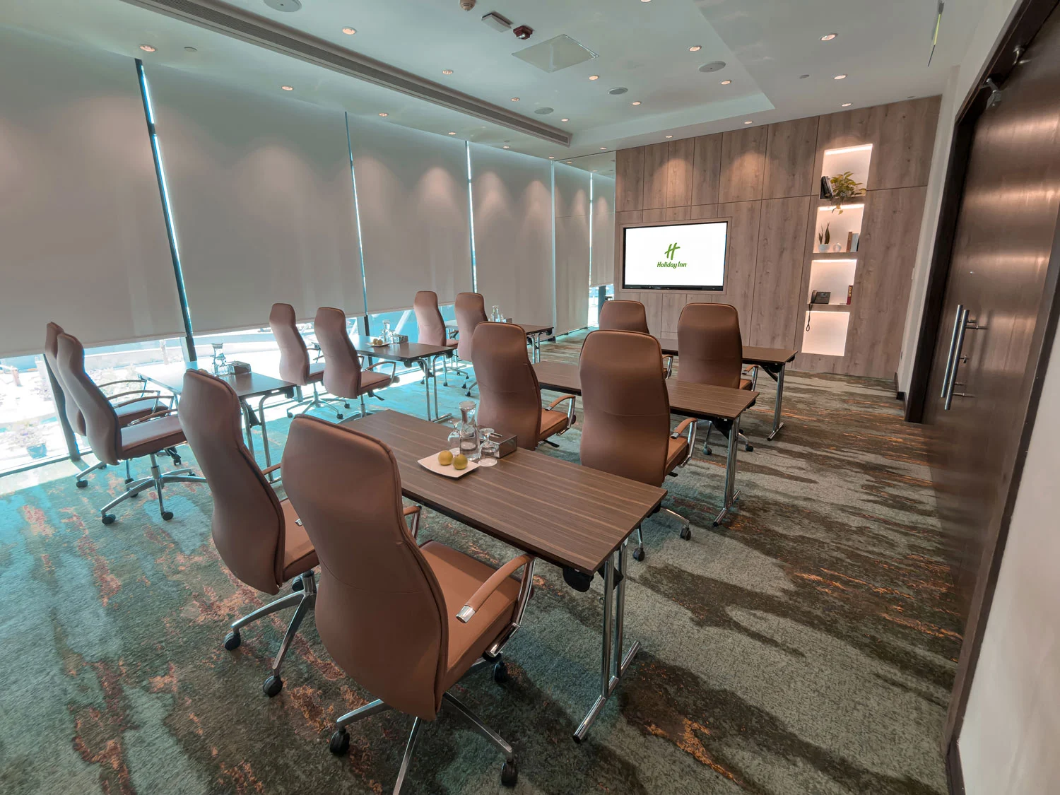 Holiday Inn Abu Dhabi meeting room with screen and desks.