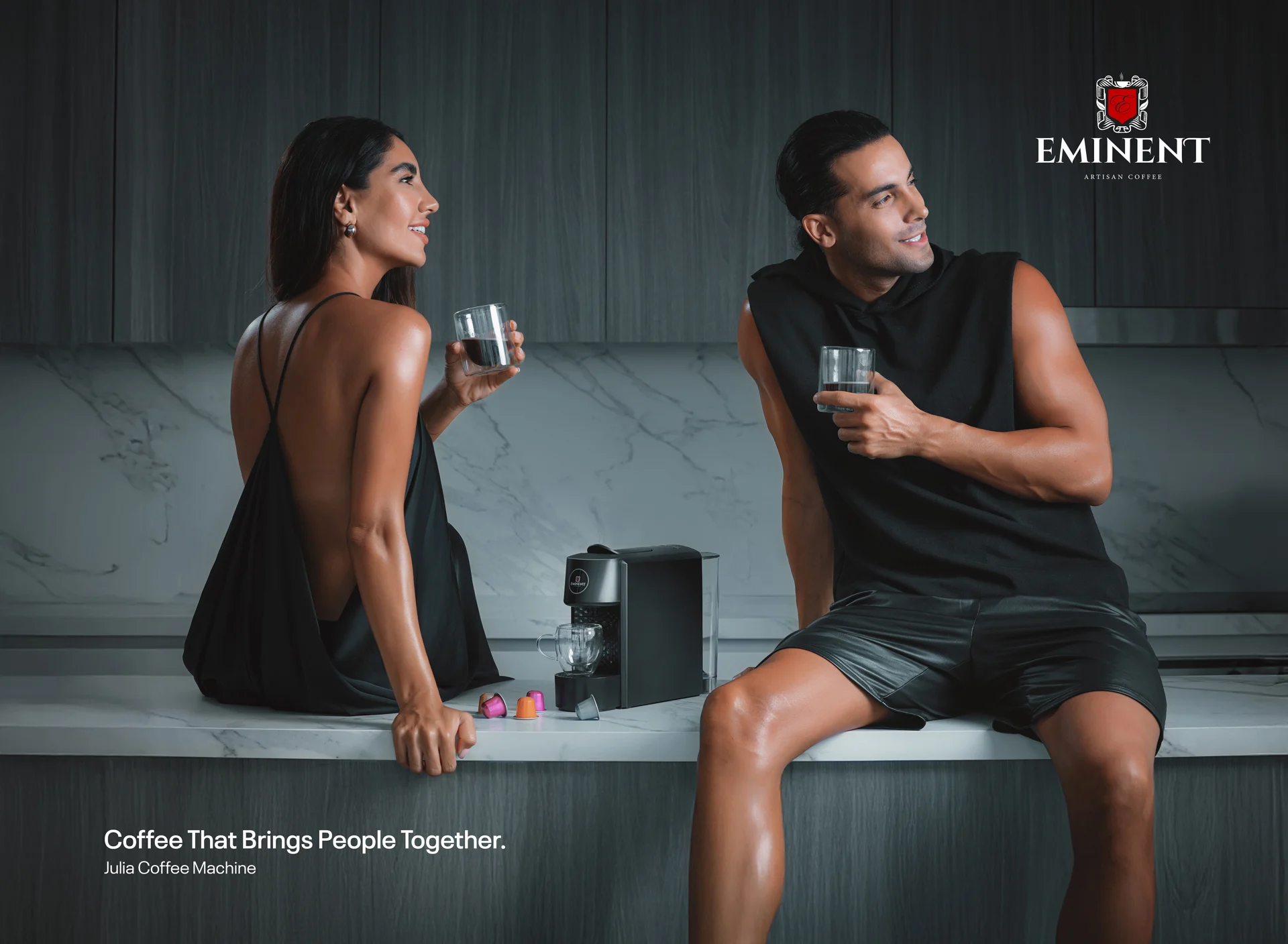 Lifestyle scene with models drinking coffee beside an Eminent coffee machine.