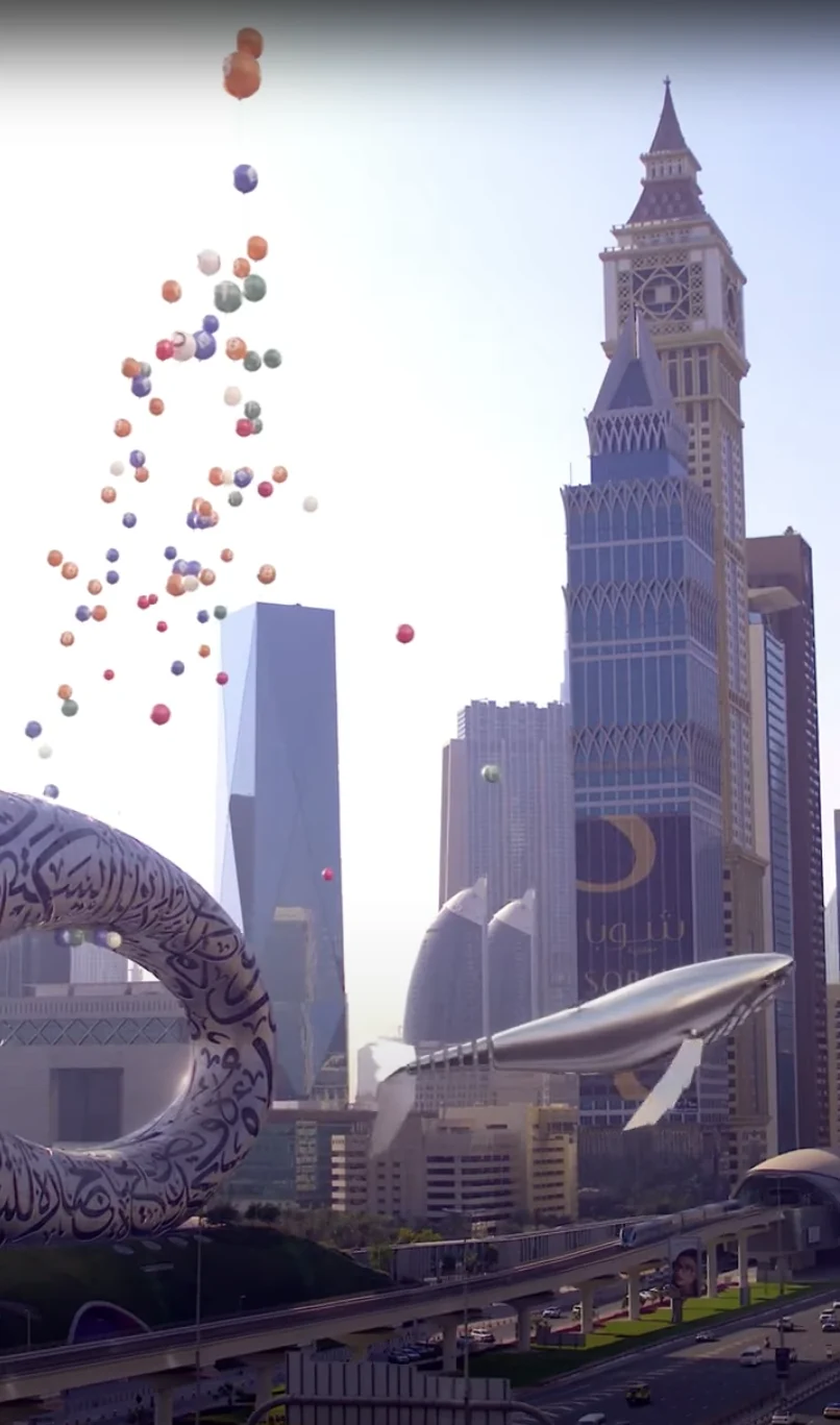 Metal whale beside Museum of the Future with colorful floating coins.